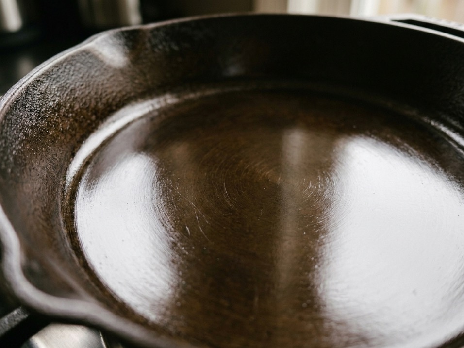 Close-up of a machined cast iron skillet surface showing smooth seasoned patina with oil sheen