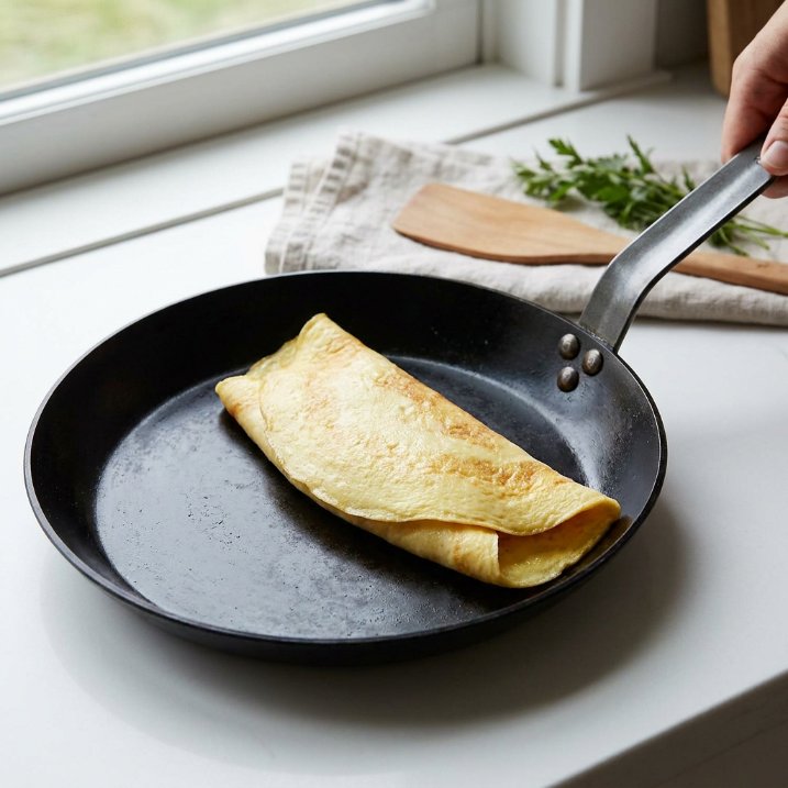 de Buyer Mineral B carbon steel pan with dark seasoning releasing an omelette cleanly