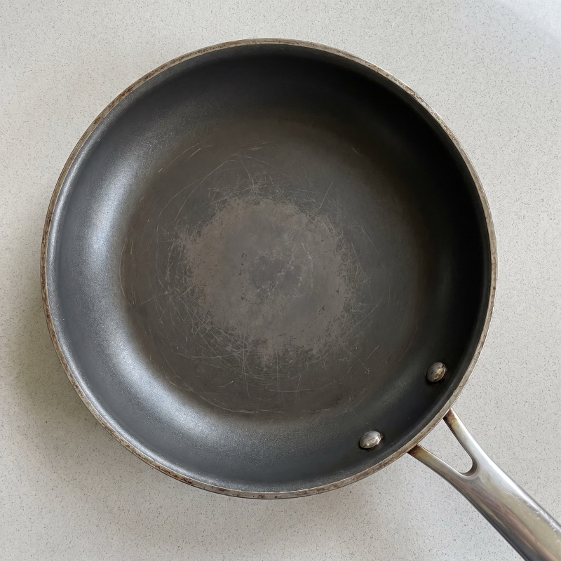 Nonstick pan interior showing worn matte center and intact glossy edges after months of cooking
