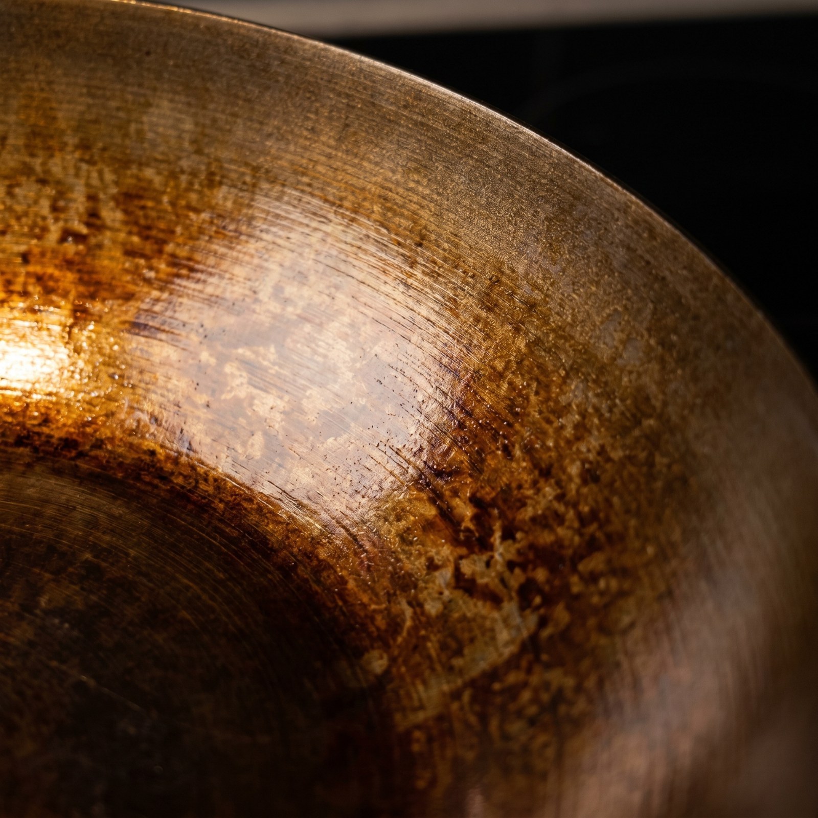 Macro close-up of carbon steel wok seasoning layer showing amber polymerized oil texture