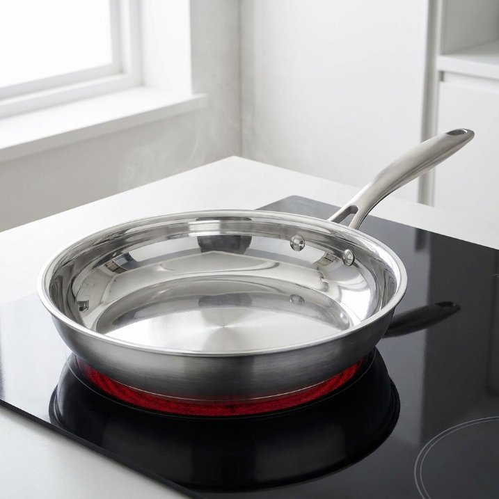 Empty stainless steel frying pan preheating on an electric glass top
