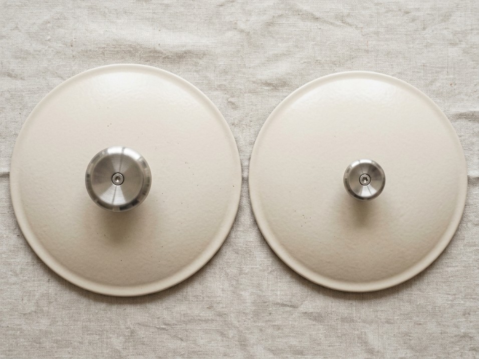Two dutch oven lids from overhead, showing a larger knob on one lid and a smaller knob on the other