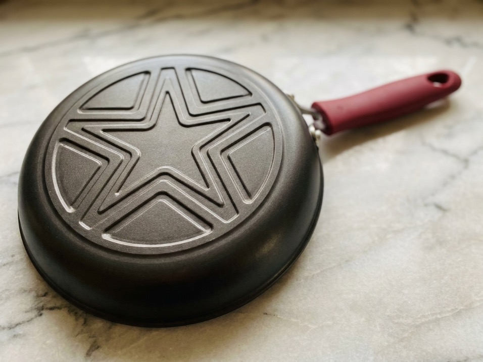 Close-up of pan bottom with star pattern showing heat distribution technology on marble countertop