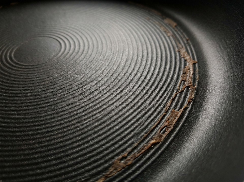 Extreme close-up of a nonstick pan's ridged cooking surface with residue caught along the grooves